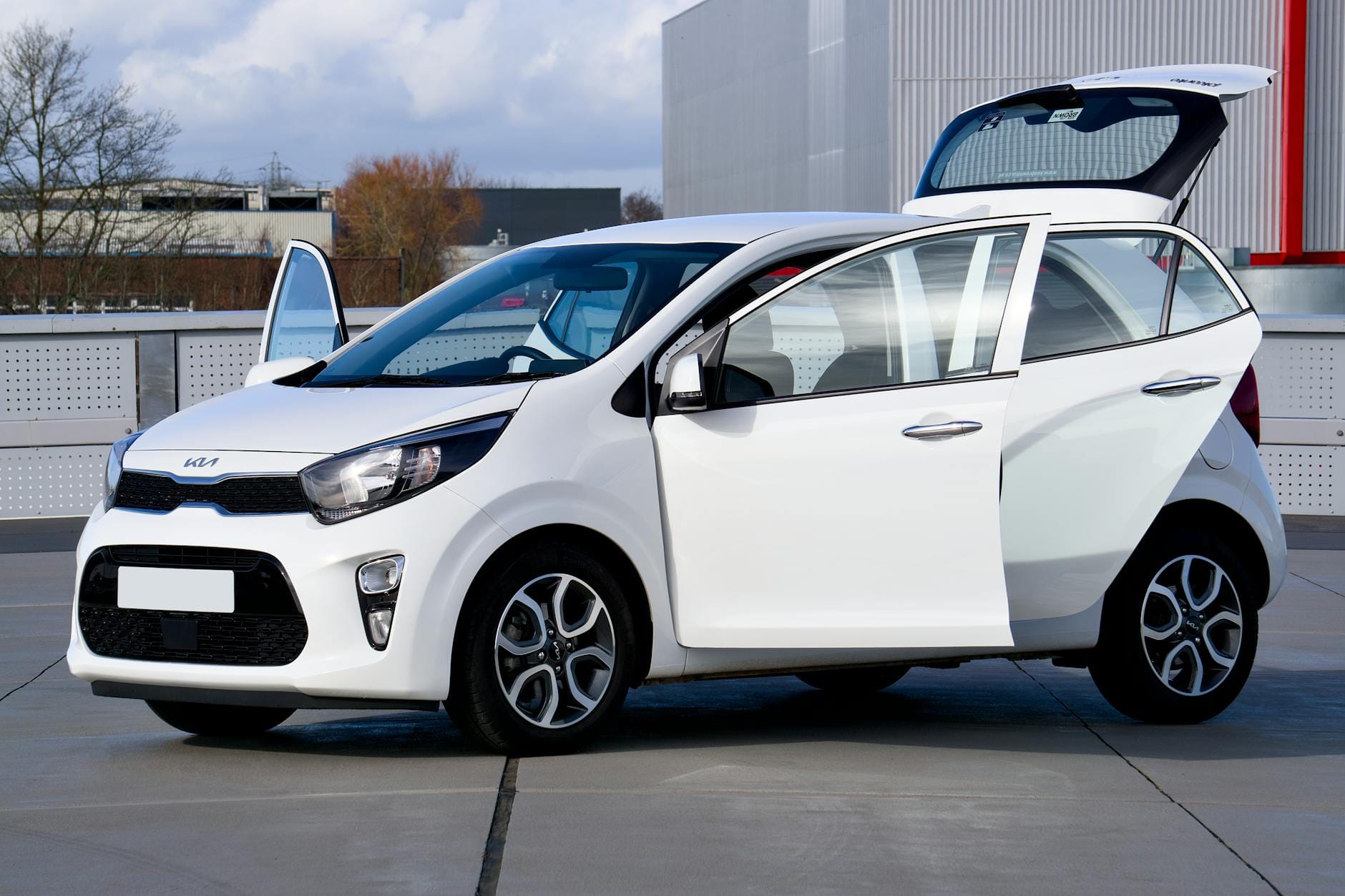 Białe kompaktowe auto z otwartymi drzwiami na ulicy w mieście