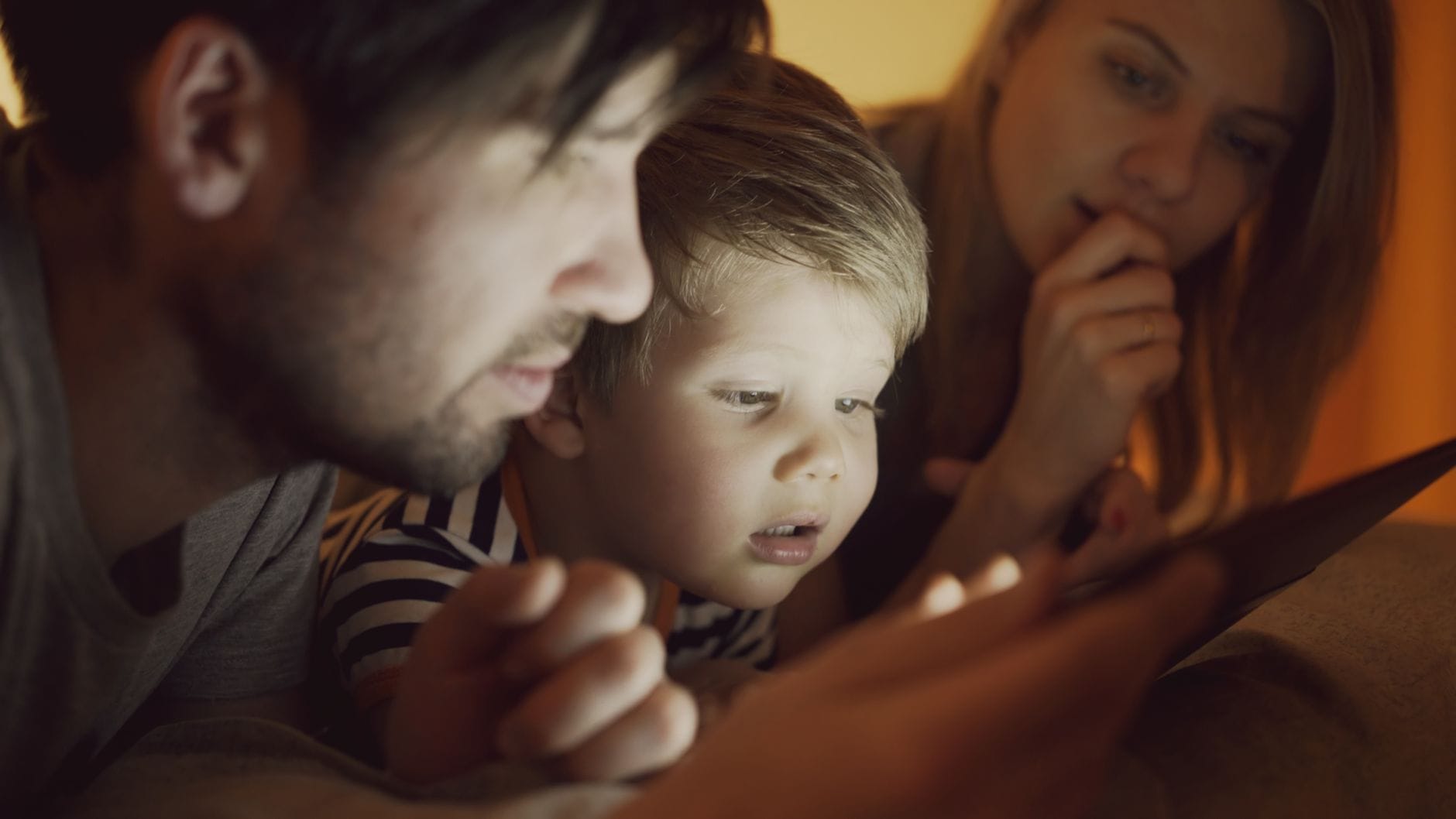 Rodzice i dziecko oglądają razem tablet w domu